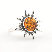 Silver ring with a sun design and amber stone on a white background