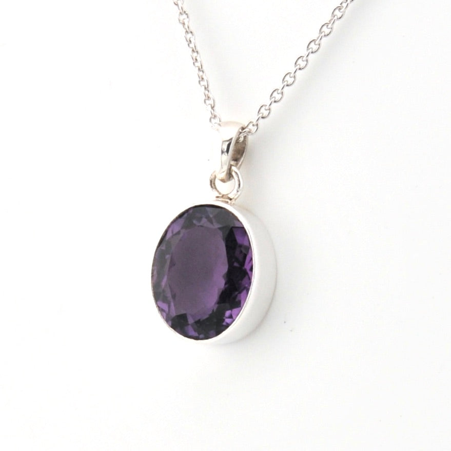 Silver necklace with a purple gemstone pendant on a white background