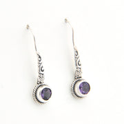 Silver earrings with purple gemstones on a white background