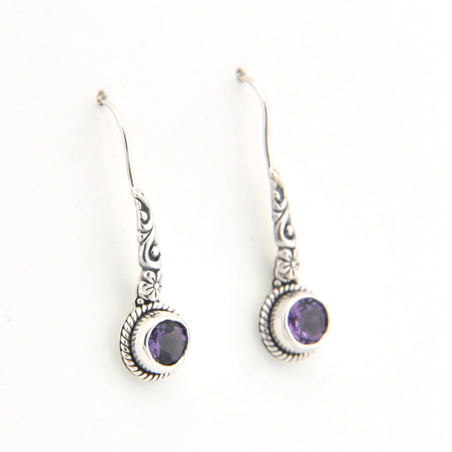 Silver earrings with purple gemstones on a white background