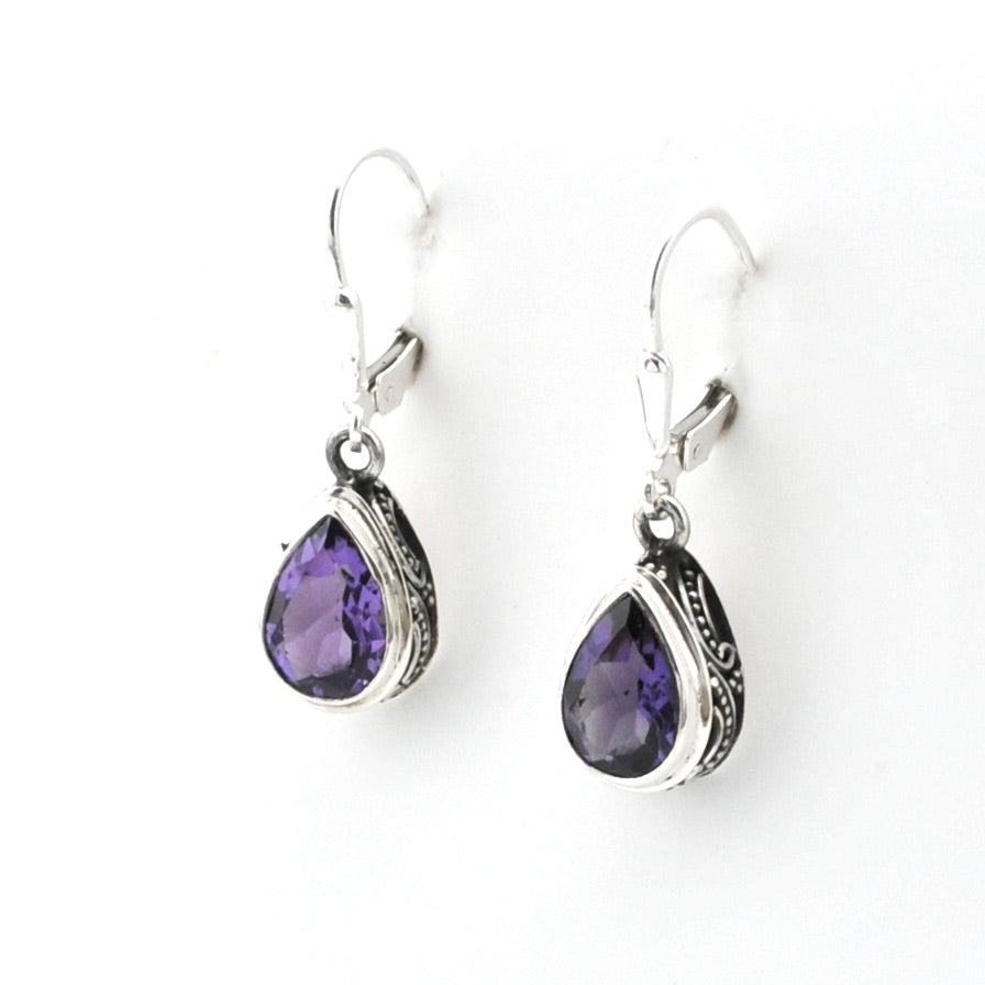 Pair of silver earrings with purple teardrop stones on a white background