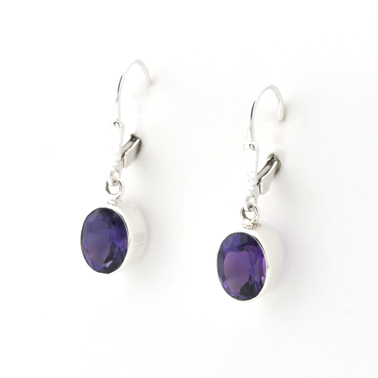 Pair of silver earrings with purple gemstones on a white background
