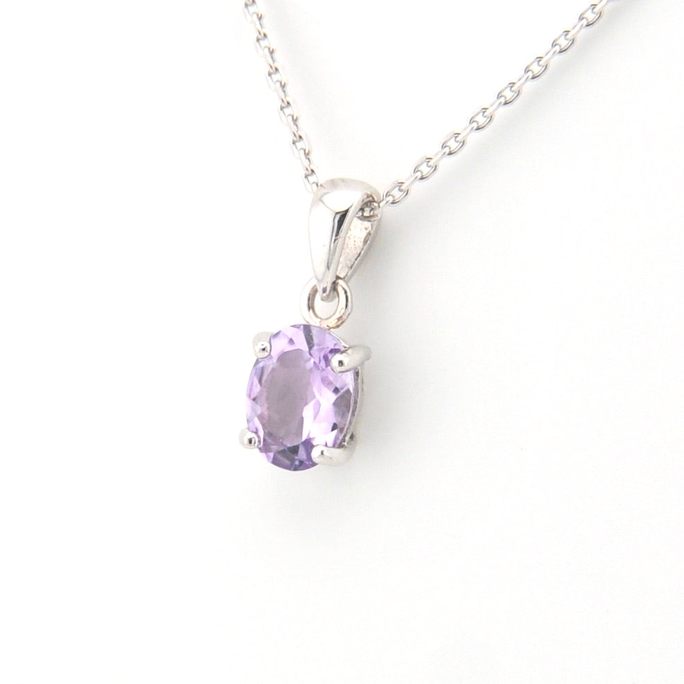 Silver pendant with a purple gemstone on a white background