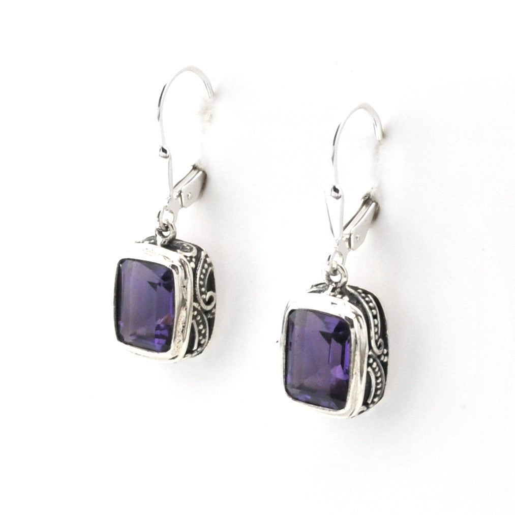 Pair of silver earrings with purple gemstones on a white background