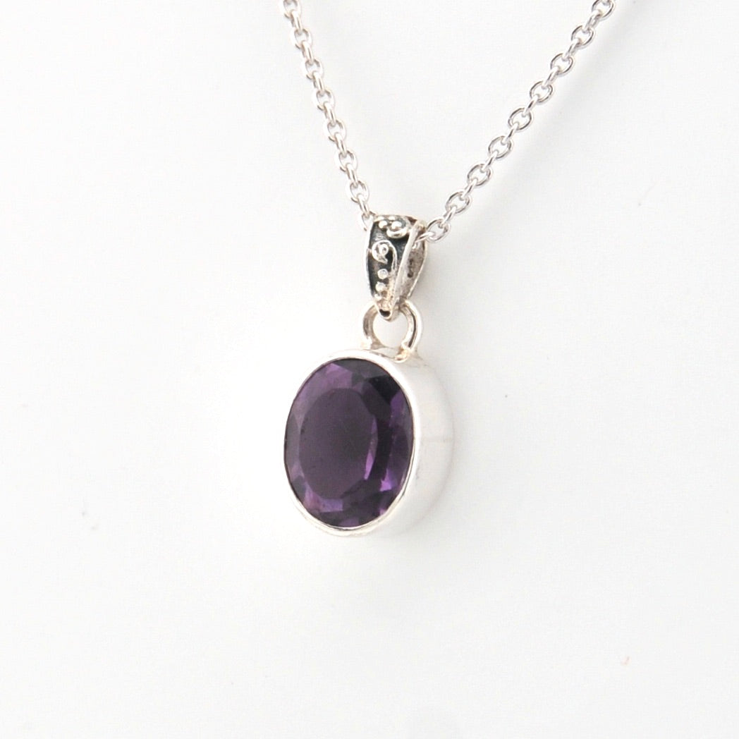 Silver necklace with a purple gemstone pendant on a white background