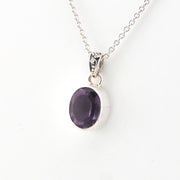 Silver necklace with a purple gemstone pendant on a white background
