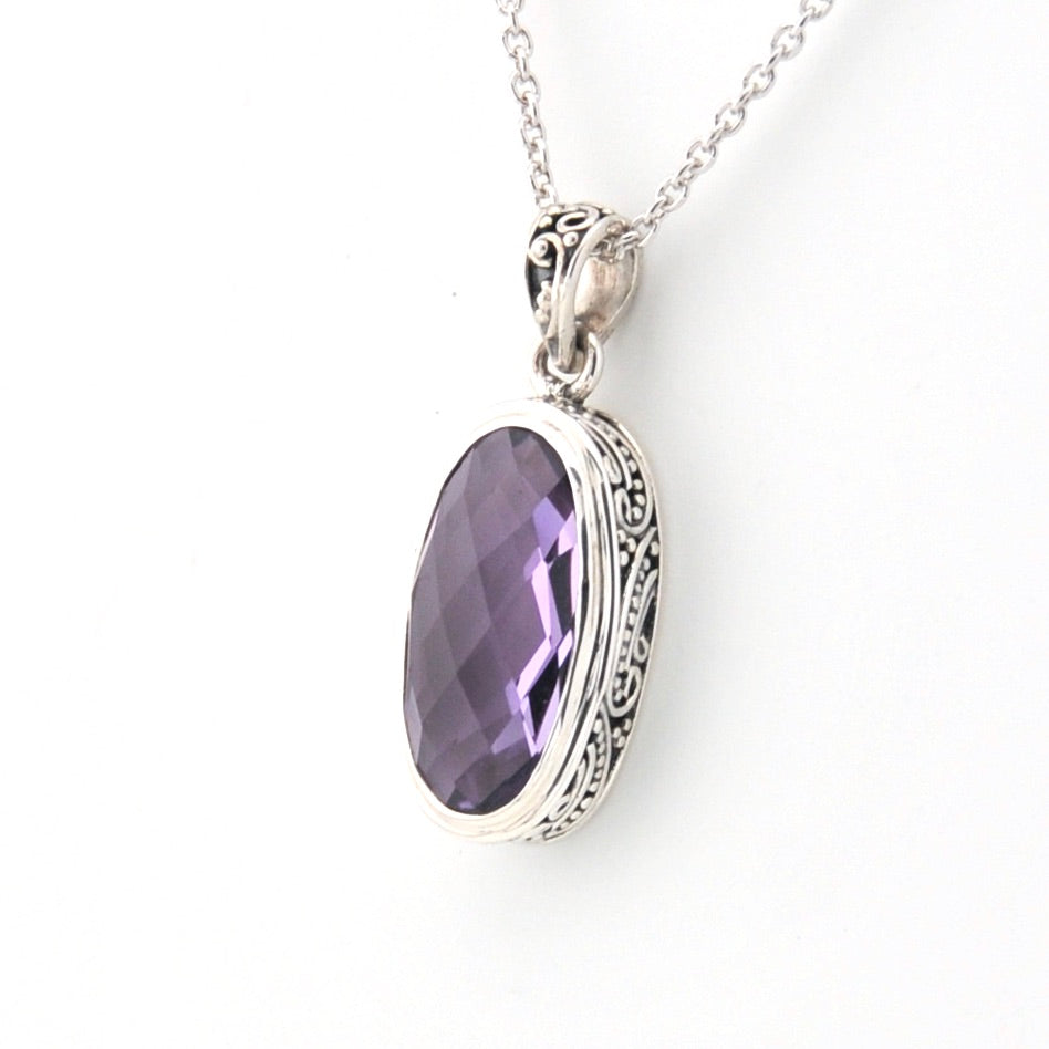 Silver pendant with a purple gemstone on a white background