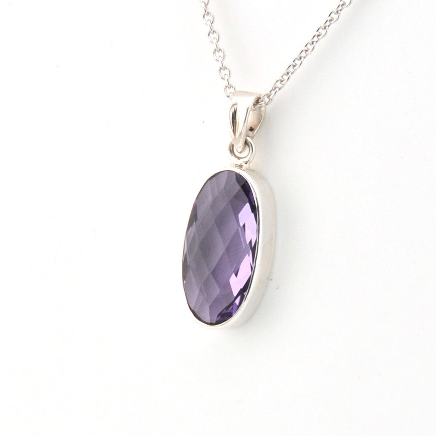 Silver necklace with a purple gemstone pendant on a white background