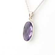 Silver necklace with a purple gemstone pendant on a white background