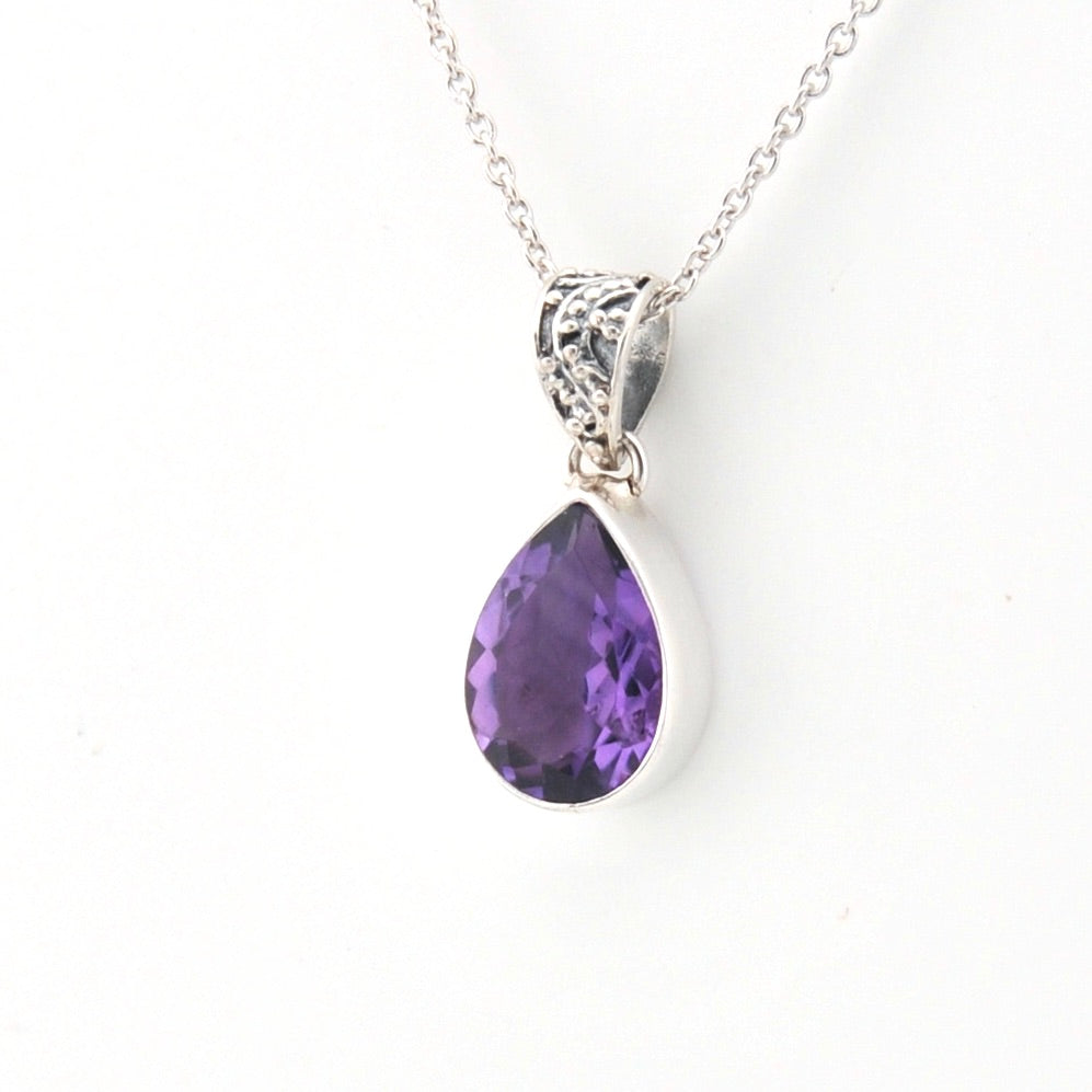 Purple teardrop pendant on a silver chain against a white background