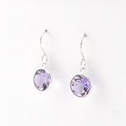 Pair of silver earrings with purple gemstones on a white background
