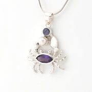 Silver crab pendant with purple gemstones on a white background
