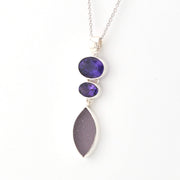 Necklace with purple gemstones and a marquise shaped piece of sea glass pendant on a white background