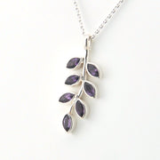 Silver necklace with a leaf-shaped pendant featuring purple stones on a white background