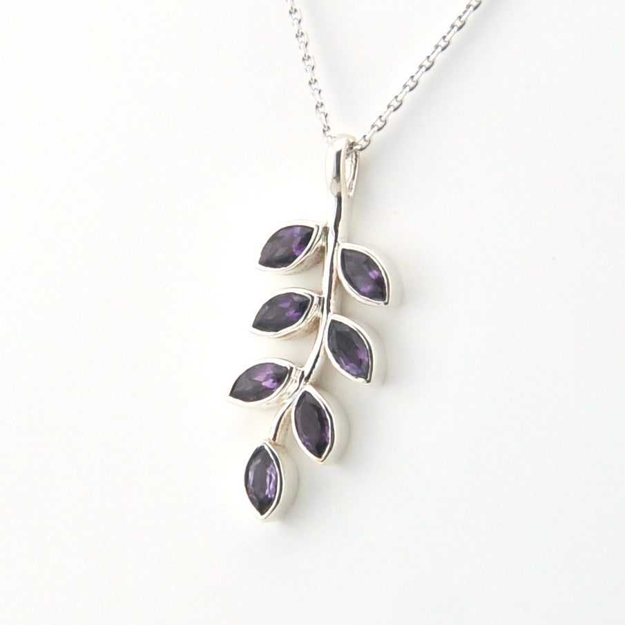 Silver necklace with a leaf-shaped pendant featuring purple stones on a white background