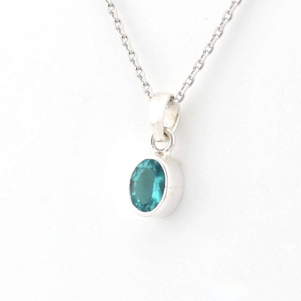 Silver necklace with a pendant featuring a green gemstone on a white background