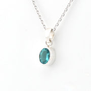 Silver necklace with a pendant featuring a green gemstone on a white background