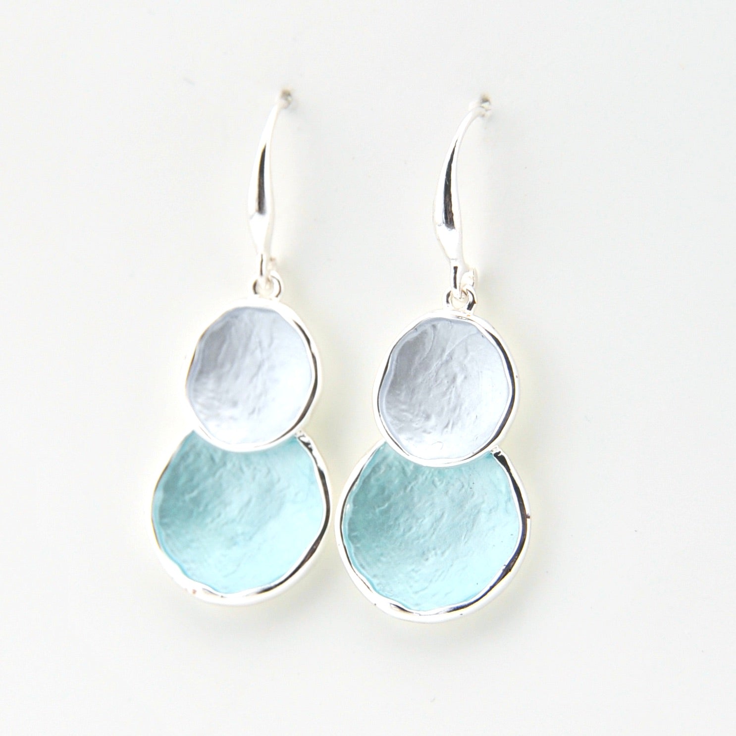 Pair of earrings with two circular discs, one silver and one light blue, on a white background.