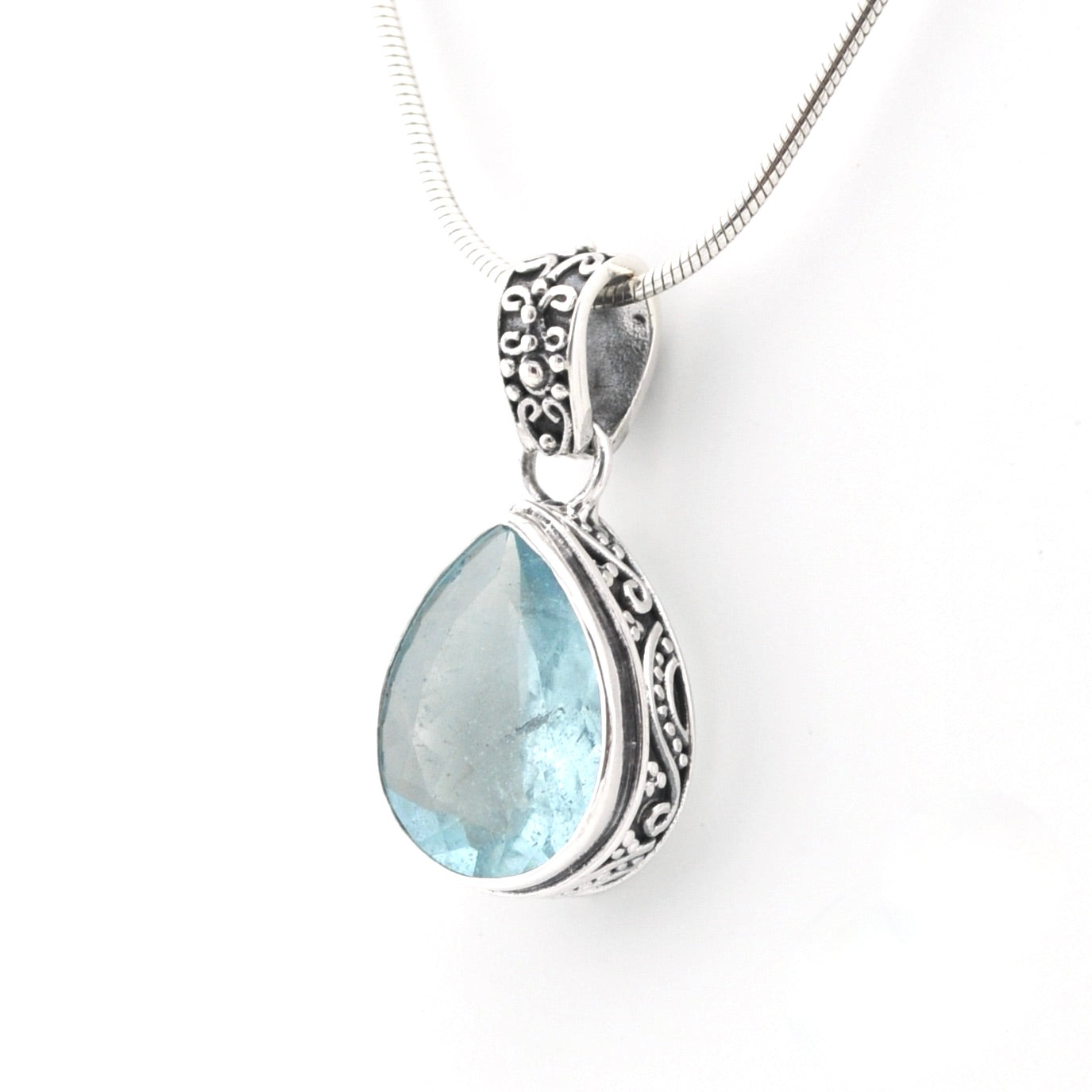Silver pendant with a teardrop-shaped blue gemstone on a white background