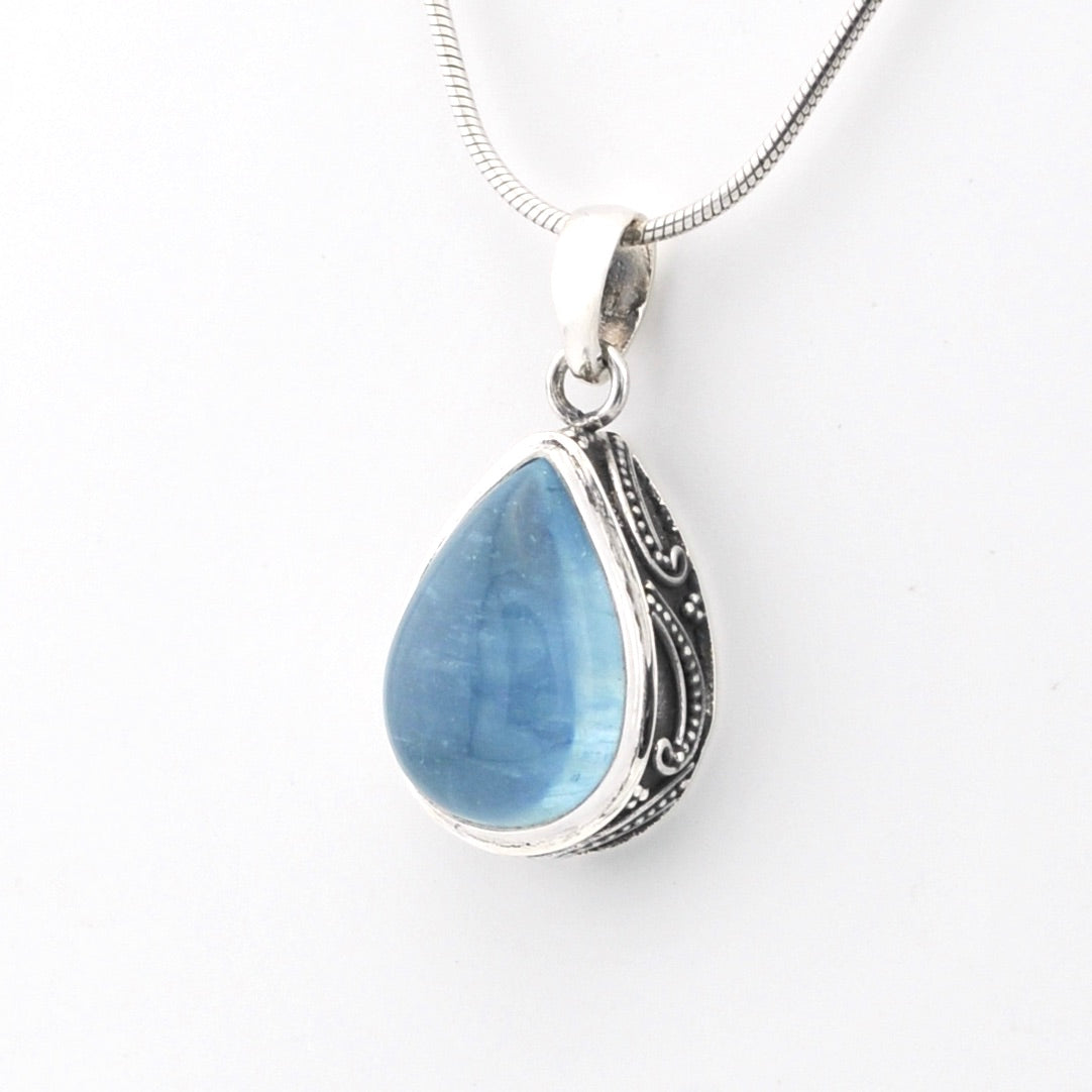 Teardrop-shaped blue pendant with silver frame on a white background