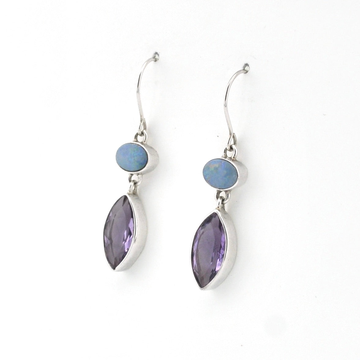 Pair of silver earrings with purple and blue stones on a white background