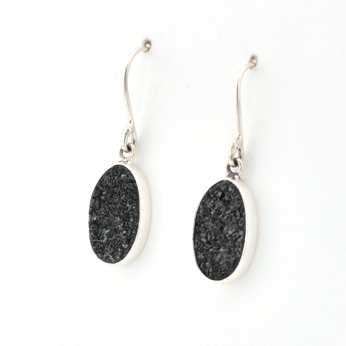 Black oval earrings with silver hooks on a white background