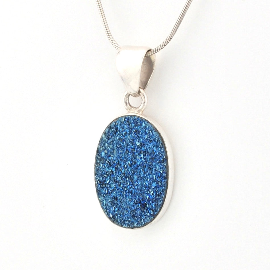 Blue druzy pendant on a silver chain against a white background