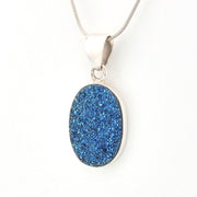 Blue druzy pendant on a silver chain against a white background