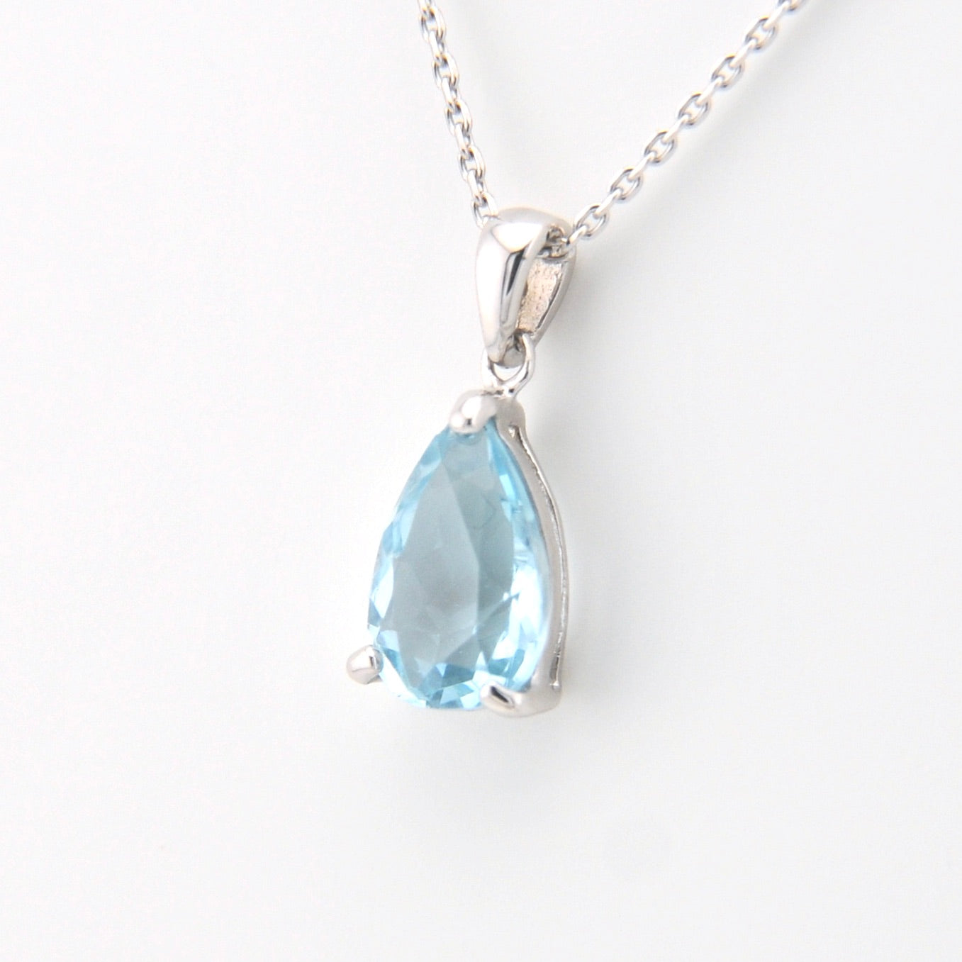 Teardrop-shaped blue gemstone pendant on a white background