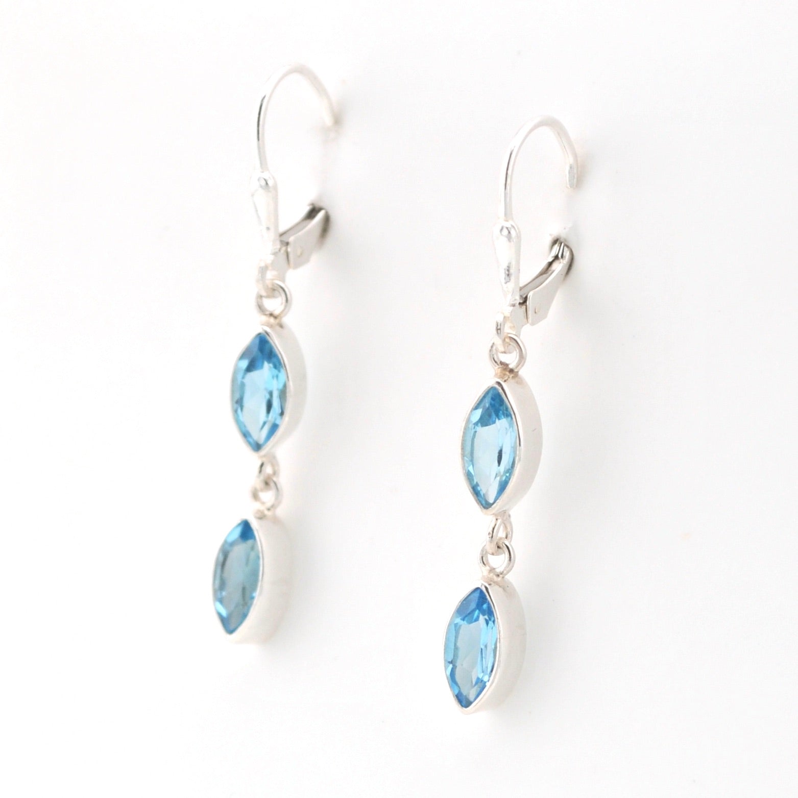 Silver earrings with blue gemstones on a white background
