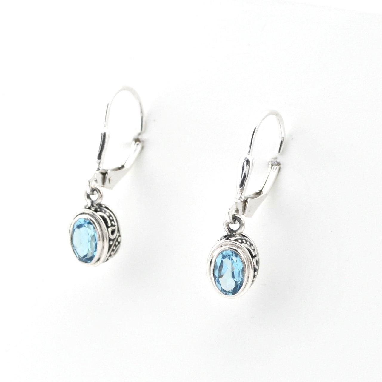 Silver earrings with blue gemstones on a white background
