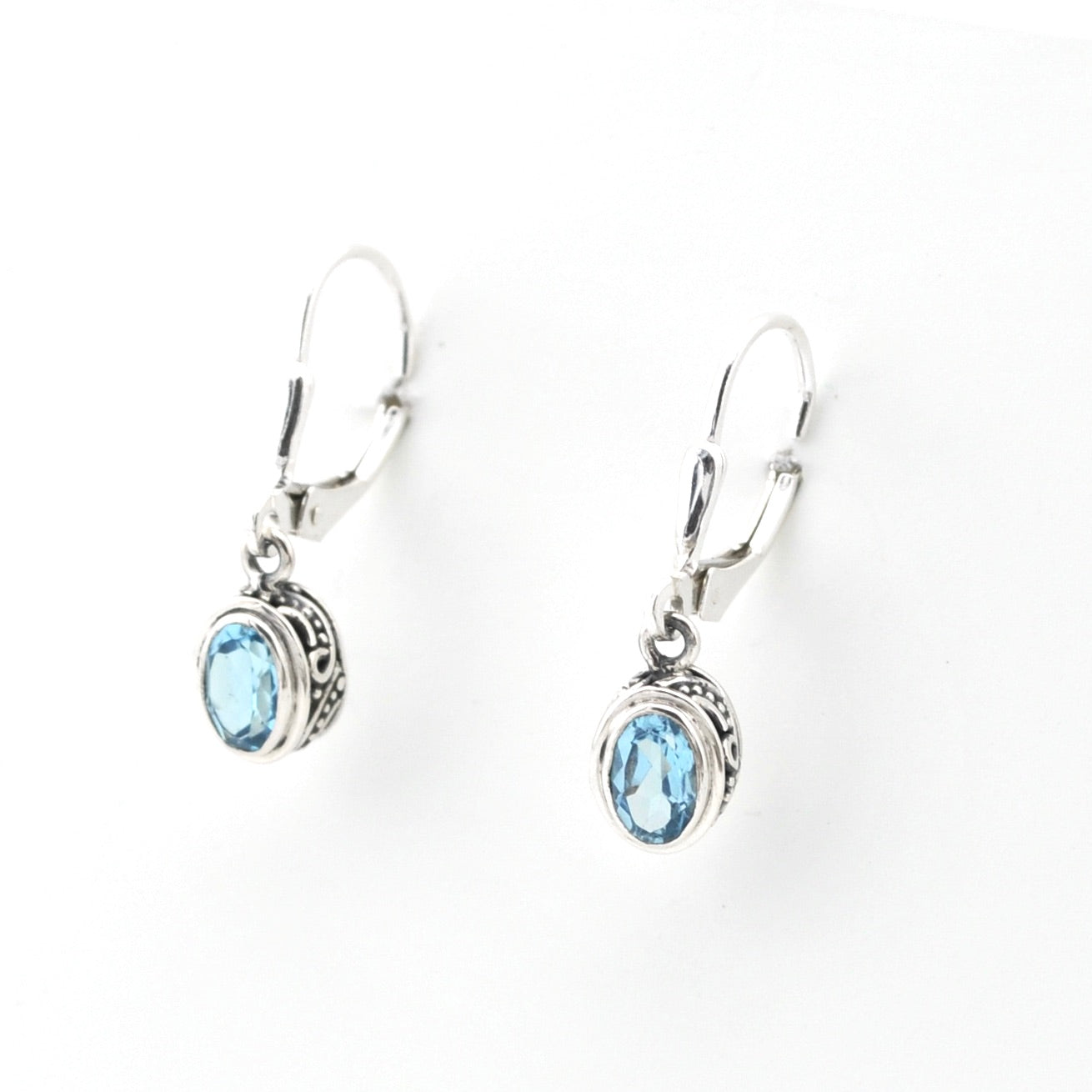 Silver earrings with blue gemstones on a white background