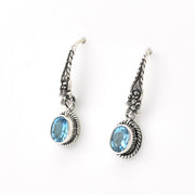 Pair of silver earrings with blue gemstones on a white background