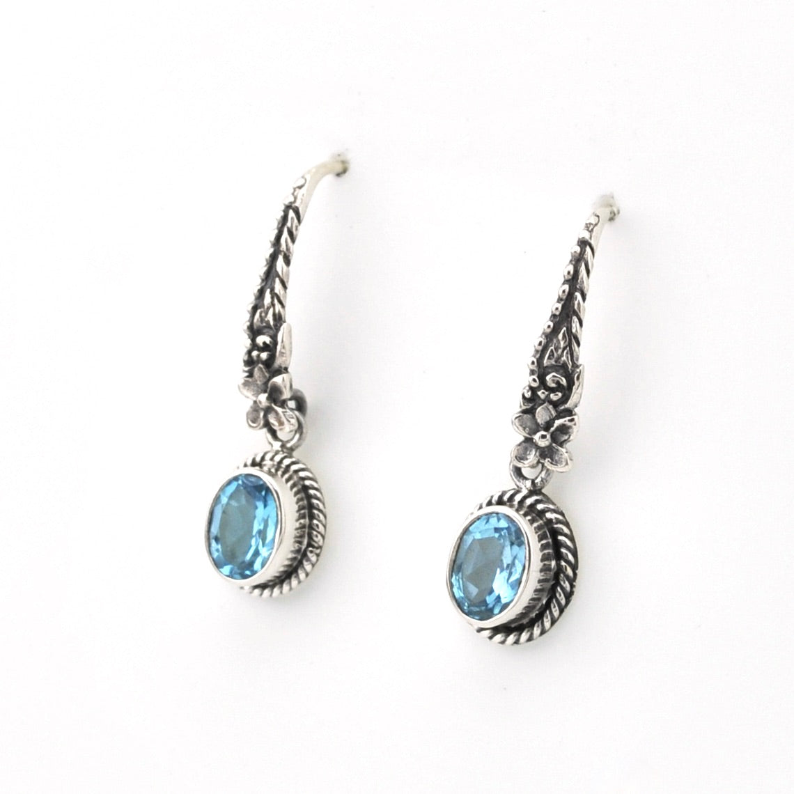 Pair of silver earrings with blue gemstones on a white background