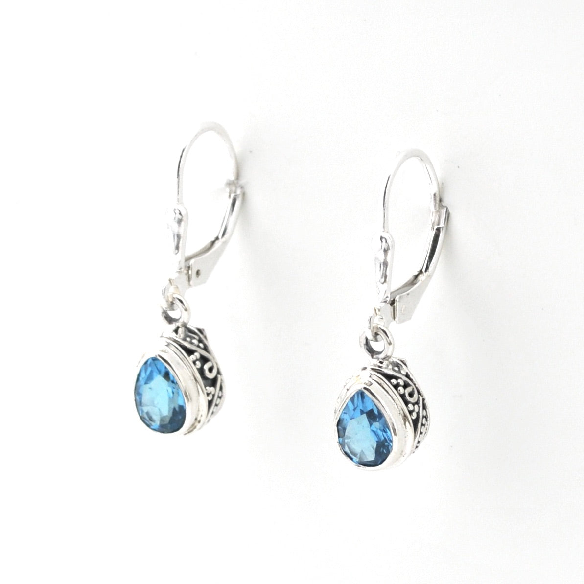 Silver earrings with blue gemstones on a white background