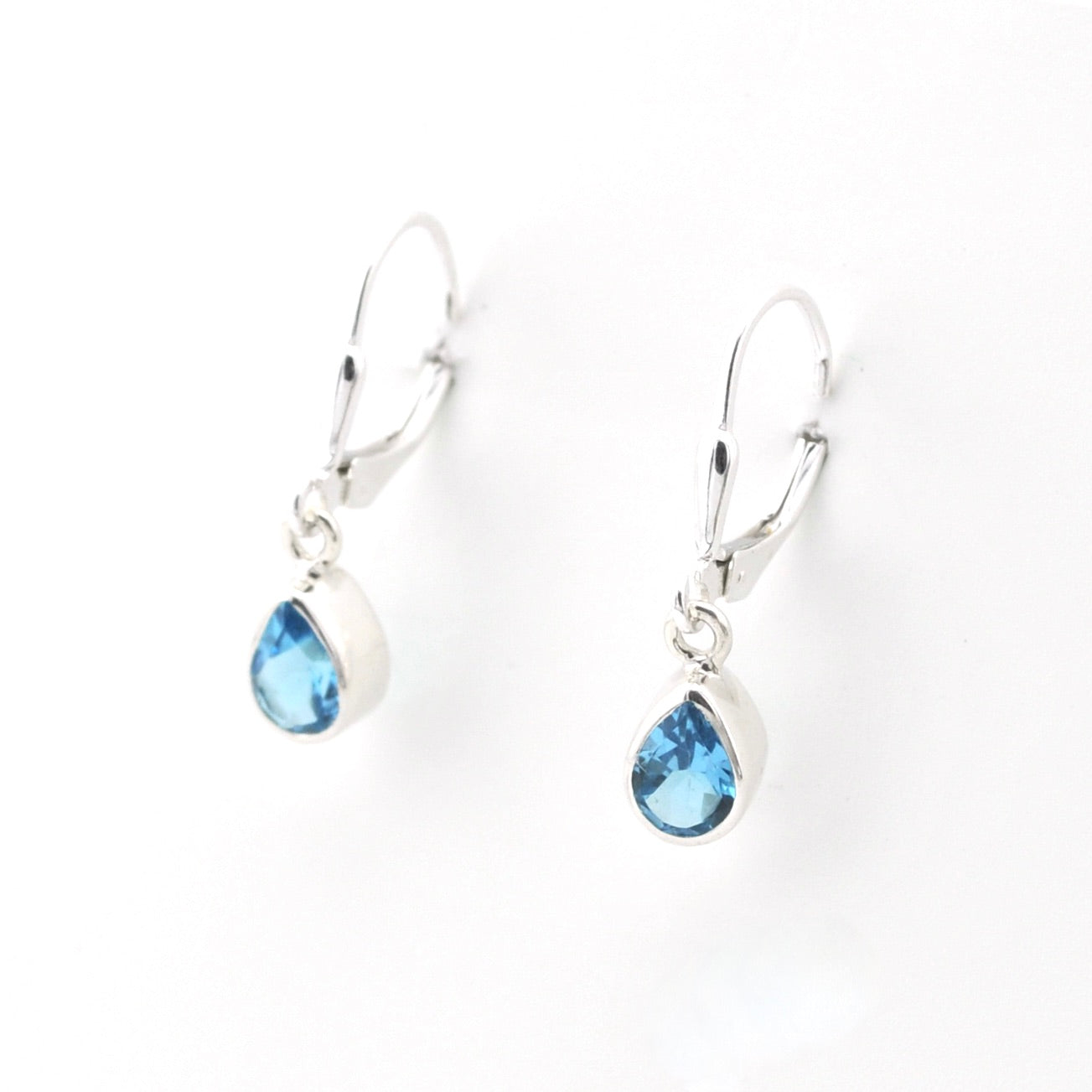 Silver earrings with blue teardrop-shaped gemstones on a white background