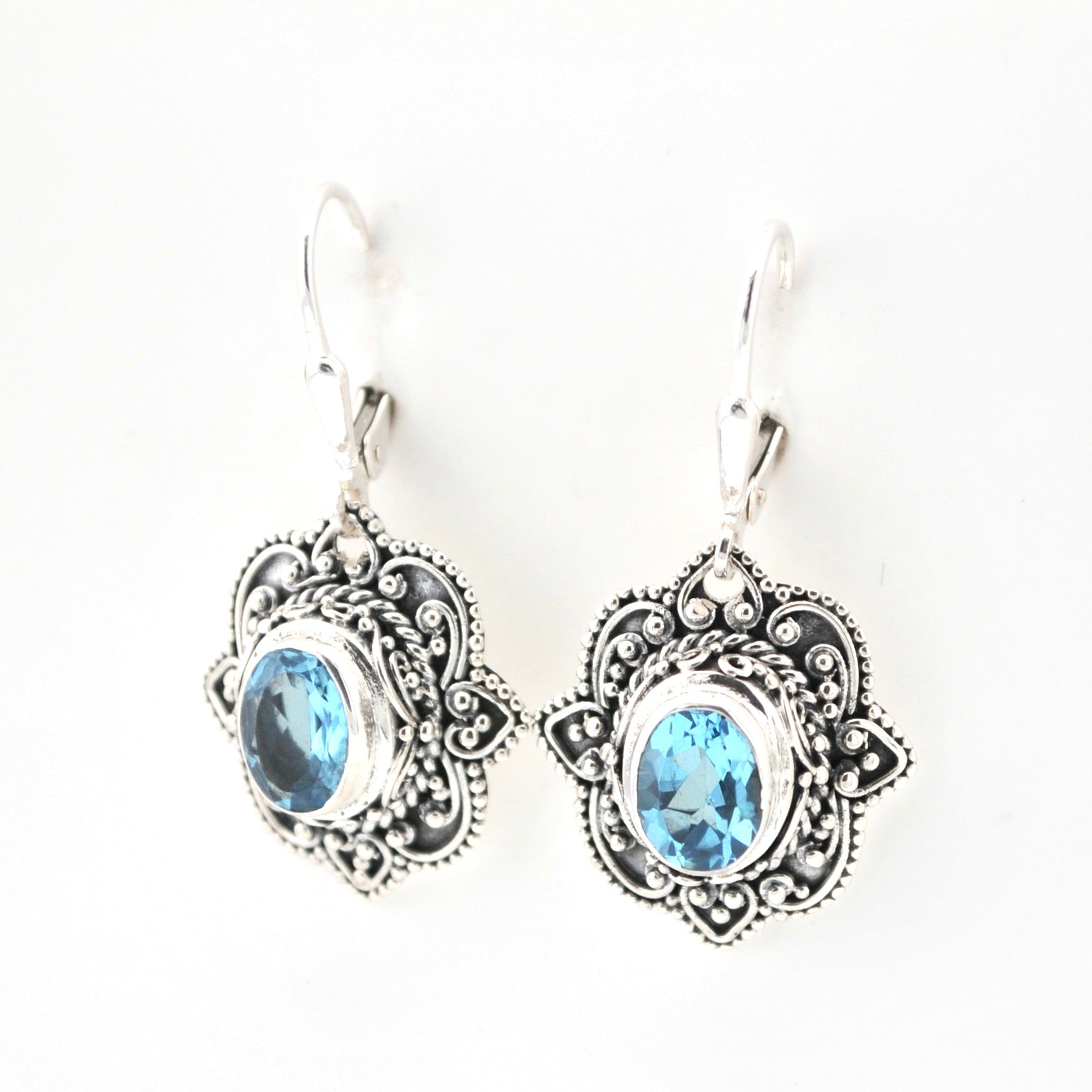 Silver earrings with blue gemstones on a white background