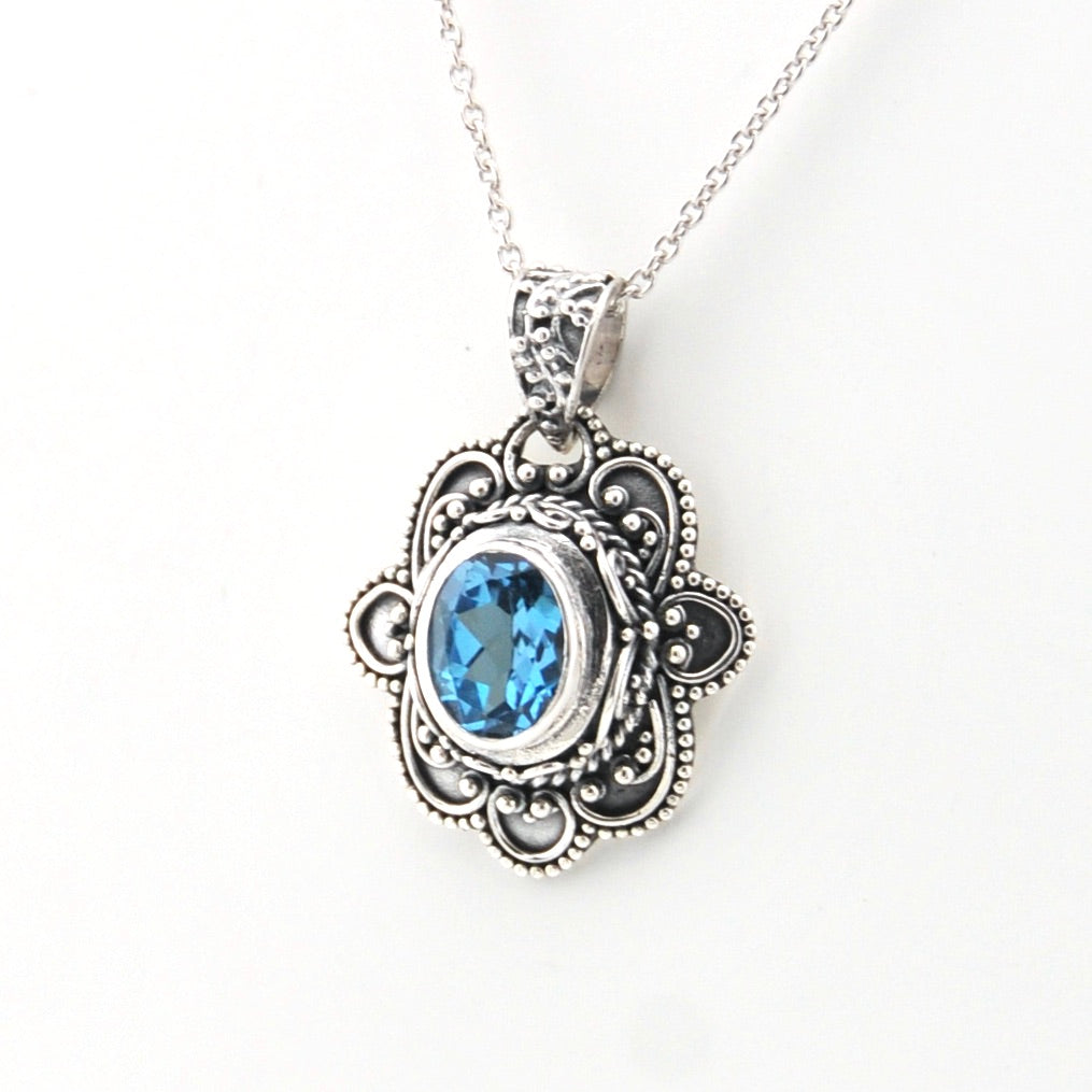 Silver pendant with blue gemstone on a white background