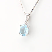 Silver necklace with a blue gemstone pendant on a white background