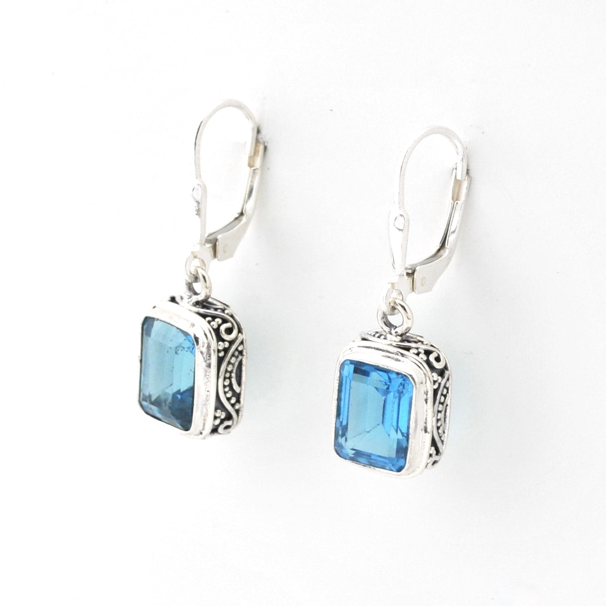 Silver earrings with blue gemstones on a white background
