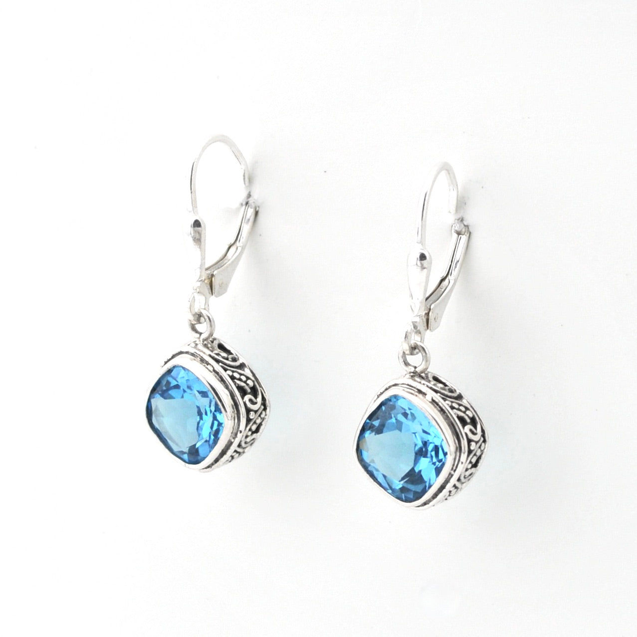 Silver earrings with blue gemstones on a white background