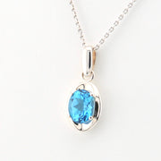 Silver necklace with a blue gemstone pendant on a white background