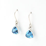 Pair of silver earrings with blue trillion-shaped gemstones on a white background