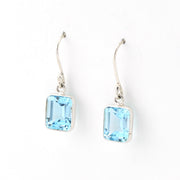Pair of silver earrings with blue gemstones on a white background