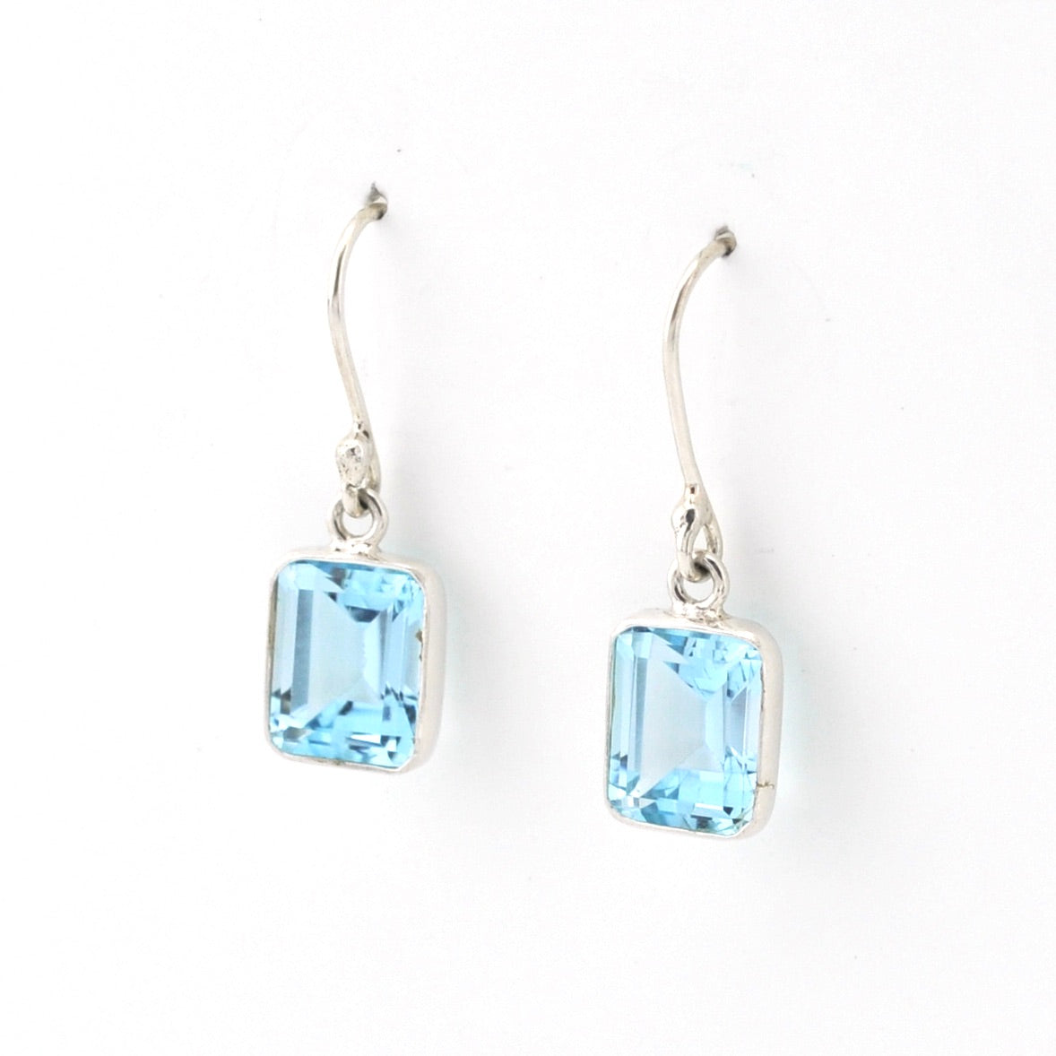 Pair of silver earrings with blue gemstones on a white background