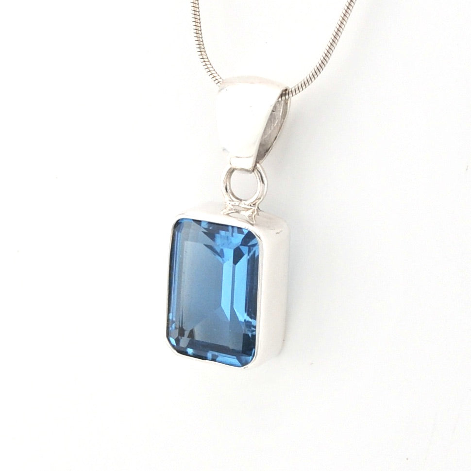 Silver necklace with a blue rectangular gemstone pendant on a white background
