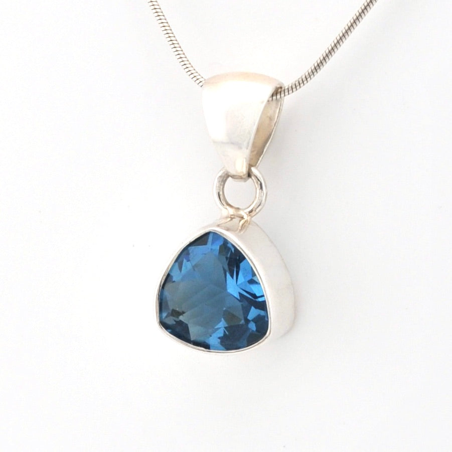 Silver pendant with a blue gemstone on a white background