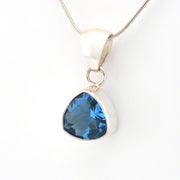 Silver pendant with a blue gemstone on a white background