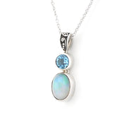 A silver pendant necklace featuring a round light blue gemstone and an oval iridescent white opal stone, suspended from a delicate silver chain on a white background.