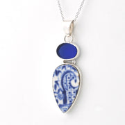 A silver pendant necklace featuring a teardrop-shaped blue and white patterned porcelain, a smaller round blue stone above it, and a silver chain against a plain white background.